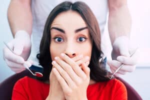 Woman covers her mouth at dentist because of dental phobia
